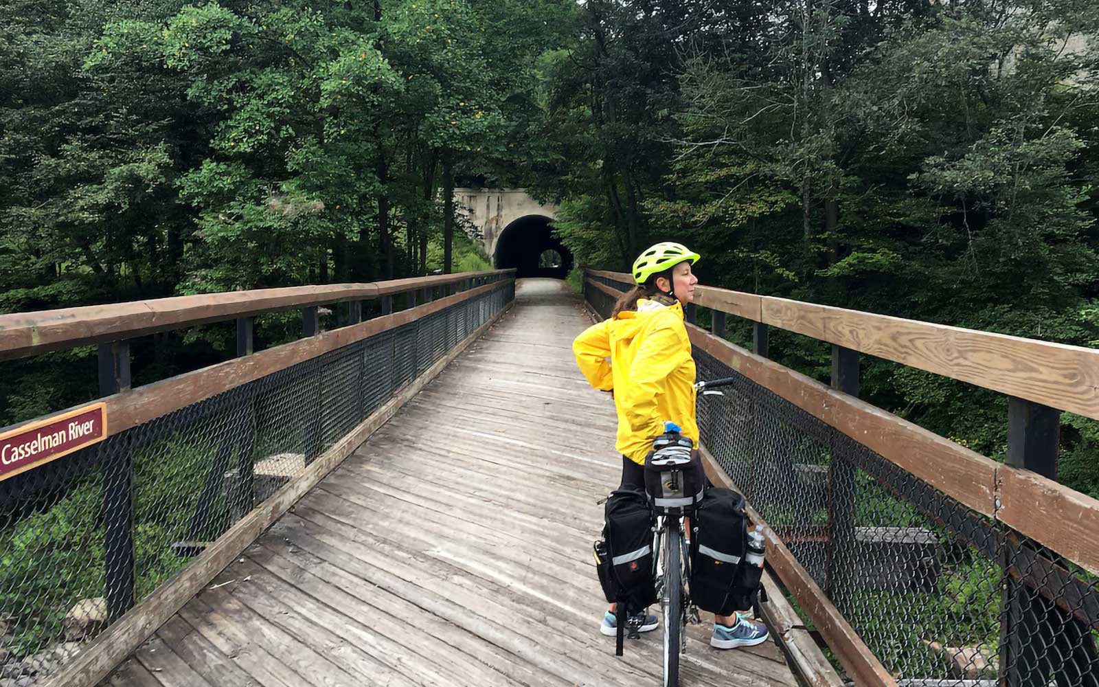 Two riders on the Casselman River bridge — shaded by green canopy